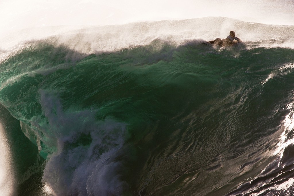 Brenden Newton paddling over big wave by Ray Collins